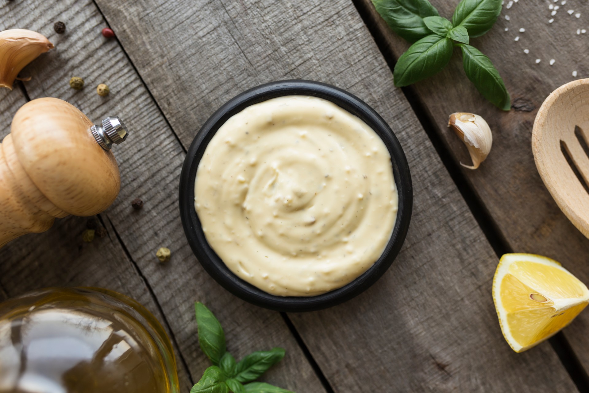 Cooking homemade mayonnaise, garlic cream sauce. Seasonings on wooden background